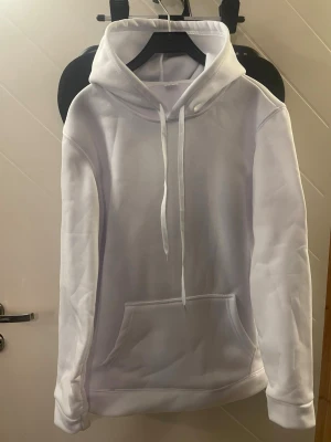 Vit hoodie - Vit hoodie i storlek M, tillverkad i 100 % polyester som är både jätte skön och varm. Den mjuka insidan ger hög komfort, medan magfickan och snören i huvan ger en klassisk och praktisk design. Perfekt för både vardag och mysiga dagar – en hoodie du gärna använder om och om igen.🌟