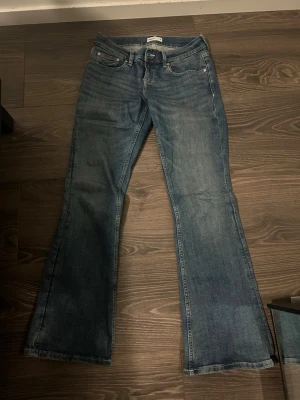 Blå bootcut jeans från Gina Tricot - Säljer ett par blå bootcut jeans från Gina tricot i storlek 38. Jeansen har låg midja och utsvängda ben. Tillverkade i denim med snygg tvättad look.
