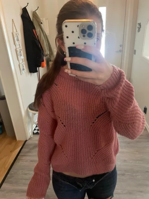 Rosa stickad tröja - Mysig rosa stickad tröja med rund hals och dekorativa hålmönster, ribbade muddar vid ärmslut och nederkant samt långa ärmar. Säljer tröjan för att den inte kommer till användning!!💝