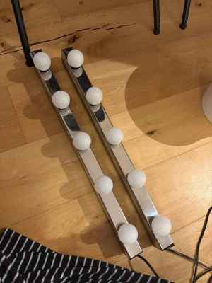 2 Sminklampor/Spegelbelysning med kromad ram - Två stycken spegelbelysningar med kromad metallram och fyra runda vita glödlampor på varje. Perfekt för sminkbord eller garderob för att få riktigt bra ljus. Snygg och modern design som ger en lyxig känsla.