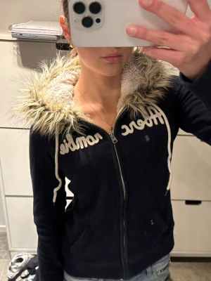 Abercrombie & fitch fur hoodie med fuskpäls  - Snygg marinblå zip up hoodie från Abercrombie & fitch  med dragkedja och vit broderad logga.                Storlek M men passar S bättre!                               Stor huva med mysig fuskpäls och vitt teddyfoder. Perfekt för en chill och trendig look. Dragsko i huvan och två fickor framtill.                          