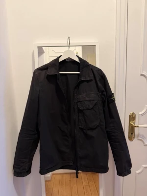 Svart overshirt  Stone Island - Svart stone overshirt, singel ficka fram. Ny patch alla dragkedjor knappar är felfritt. Vissa veck som kan steamas bort 