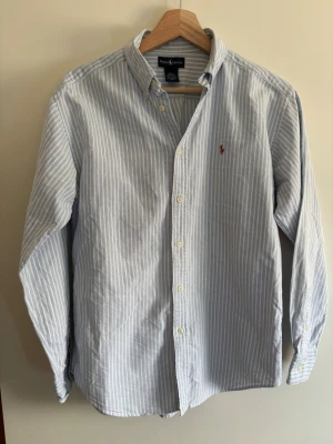 Randig ralph lauren skjorta - Stilren Blå/Vit randig ralph lauren skjorta Extremt bra skick inga defekter Storlek L16/18 vilket är XS, kolla mått nedan Skriv vid funderingar! Pris kan diskuteras!