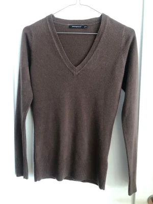 Brun V-ringad tröja Atmosphere - Mjuk brun tröja från Atmosphere med V-ringning och långa ärmar. Tröjan har en enkel, stilren design med ribbade muddar vid ärmslut och nederkant. Perfekt att matcha med jeans eller kjol för en clean look. Oklar storlek men typ som S/Xs. Lit lätt urtvättad