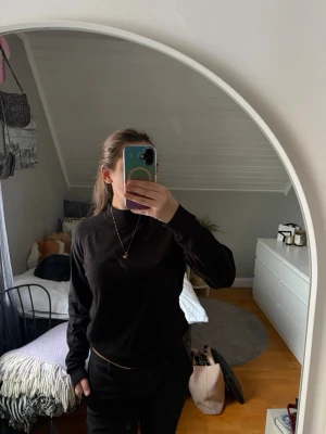 Svart långärmad tröja - En enkel och stilren svart långärmad tröja med rund halsringning. Perfekt för att matcha med jeans eller kjol och passar till många olika outfits. Tröjan har en klassisk passform och är gjord i ett mjukt material.