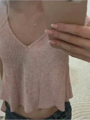 Ljusrosa ribbad croppad topp Gina Tricot - Supersöt ljusrosa croppad topp från Gina Tricot. Toppen är ribbad, har v-ringning och är ärmlös. Perfekt till jeans eller kjol för en chill och trendig look.