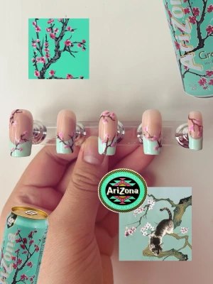 Press-on naglar med körsbärsblom - Snygga press-on naglar inspirerade av AriZona Green Tea, med mintgröna tippar och handmålade körsbärsblommor i rosa och brunt på en nude bas. Naglarna har en rak, något rundad form och ger en unik, konstnärlig look. Perfekt för dig som vill sticka ut med detaljerad nagelkonst.
