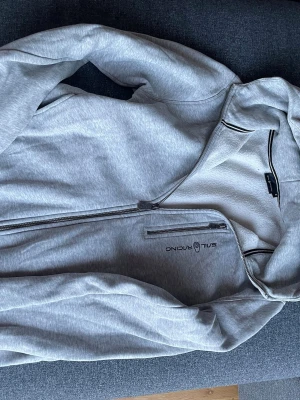 Ljusgrå ziphoodie från Sail Racing stl S - Ljusgrå hoodie från Sail Racing med dragkedja framtill och justerbar huva. 