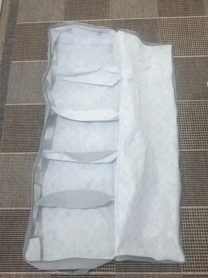 Ljusblå förvaringspåse med fack - Praktisk ljusblå förvaringspåse i tyg med flera separata fack. Perfekt för att organisera kläder, skor eller småprylar i garderoben. Påsen är rektangulär och kan vikas ihop för enkel förvaring när den inte används.