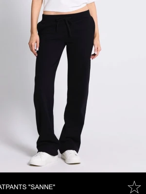 Svarta mjukisbyxor Sanne - Svarta mjukisbyxor med rak passform och dragsko i midjan från Sanne. Byxorna har en enkel och clean look, perfekta för chill dagar. Tillverkade i mjukt material som känns skönt mot huden. Matcha med sneakers och en crop top för en avslappnad vibe. Knappt använd bara testat