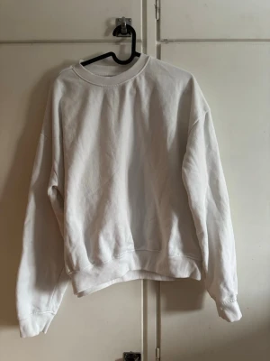 Vit oversized sweatshirt - En enkel och stilren vit sweatshirt med rund hals och ribbade muddar vid ärmslut och nederkant. Oversized passform som ger en avslappnad look. Strl S