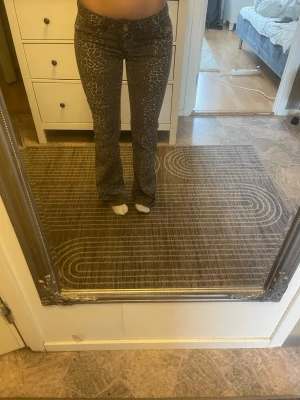 Bruna leopardmönstrade jeans - Säljer ett par bruna jeans med leopardmönster. Jeansen har bälteshällor och stängs med knapp och dragkedja. Perfekta för dig som vill sticka ut lite extra! En av hylsorna har tyvärr gått sönder 