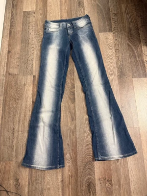 Blå bootcut jeans från Cheap Monday - Säljer ett par blå bootcut jeans från Cheap Monday med snygga slitningar och ljusa partier längs benen. 