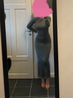 Mörkgrön långärmad långklänning - Snygg mörkgrön långklänning med lång ärm och rund halsringning. Klänningen har en tight passform och är tillverkad i ett mjukt, stretchigt material som sitter snyggt på kroppen. 