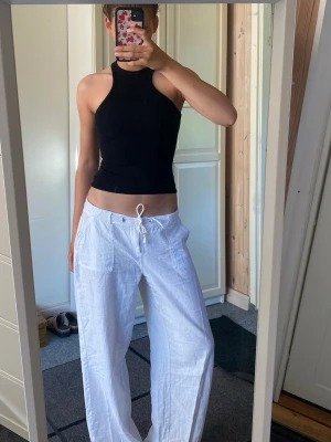 Svart croppad ärmlös topp - Säljer en svart croppad topp med hög hals och tight passform. Toppen är ärmlös och har en stilren, enkel design som passar perfekt till både jeans och kjol. Materialet känns mjukt och stretchigt, vilket gör den bekväm att bära.