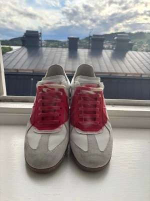Vita och röda sneakers med mockadetaljer - Snygga sneakers i vitt och rött med grå mockadetaljer på tån och sidorna. Skorna har vita och röda partier i läder och en klassisk gummisula. Perfekta för dig som gillar retrostil och vill sticka ut med färgade detaljer.