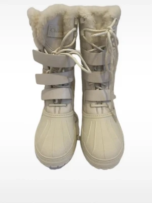 Christian Dior Snowboots - Säljer ett par vita moon boots med högt skaft och fluffig fuskpäls runt kanten. Skorna har snörning framtill och breda kardborreband för extra support. Yttermaterialet är vattenavvisande och insidan är fodrad för maxad värme. Perfekta för kalla vinterdagar. Skorna är i storlek 38 och från Christian Dior. De kostar 13000 på versatile 💞