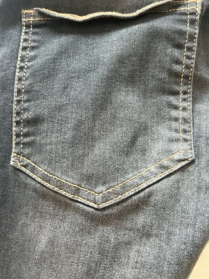 Mörkgrå raka jeans med kontrastsömmar - Säljer ett par mörkgrå jeans med raka ben och klassisk femficksdesign. Jeansen har kontrastsömmar i gult och är tillverkade i mjukt denimtyg. Perfekta för dig som gillar en enkel men stilren look.