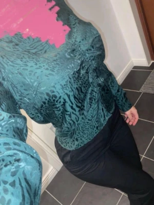 Grön mönstrad blus - Snygg grön blus med djurmönster och långärmad design. Blusen har en lätt glansig finish och en avslappnad passform. Storlek M men passar S.
