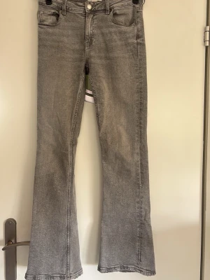 Ginatricot Grå bootcut jeans  - Säljer ett par grå bootcut jeans med klassisk femficksdesign och normalhög midja. Jeansen har en lätt utsvängd passform nedtill och är tillverkade i ett mjukt denimtyg. Referens är 155 cm. Obs säljer endast via plicks köpknapp. 