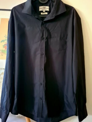 Svart skjorta - Klassisk svart skjorta från Hampton Republic i regular fit. Skjortan har långa ärmar, bröstficka och knäppning framtill. 