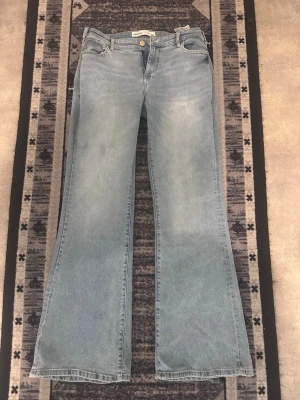 Ljusblå bootcut jeans Bershka - Säljer ett par ljusblå jeans från Bershka med utsvängda ben och klassisk femficksmodell. Jeansen har en snygg tvättad look och stängs med dragkedja och knapp. Perfekta för dig som gillar retrostil och vill ha ett par bekväma jeans med mycket attityd.