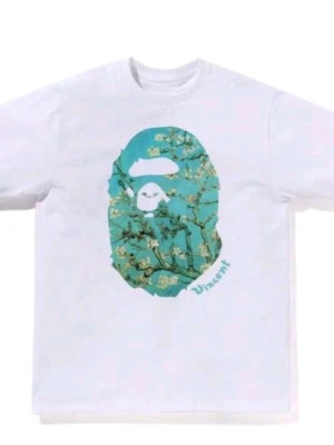 Vit bape t-shirt med konstnärligt tryck - Säljer en vit t-shirt med ett stort konstnärligt tryck på bröstet i blå och gröna toner, inspirerat av Vincent van Gogh. T-shirten har korta ärmar och en klassisk passform. Perfekt för dig som gillar streetwear och unika prints.