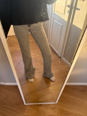 Grå bootcut jeans från Nelly  - Säljer ett par grå bootcut jeans från Nelly med klassisk kontrastsöm och ikonisk W-brodyr på bakfickan. Jeansen har hög midja och är tillverkade i ett slitstarkt denimtyg. Perfekta för en avslappnad och trendig look.
