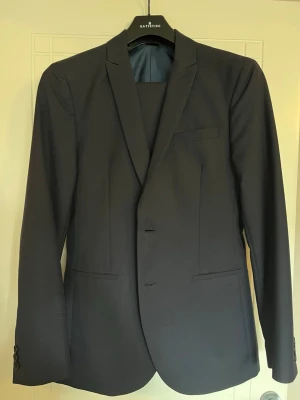 Mörkblå kostym från KIOMI - Snygg mörkblå kostym från KIOMI med klassisk passform och stilren design. Kavajen har två knappar framtill, smala slag och flera fickor. Perfekt för dig som vill ha en enkel och modern look. Använd vid avslutning 9an och student för kille 180-187cm, normalbyggd. 