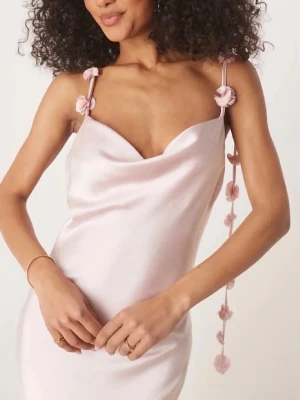 Ljusrosa långklänning med blomdetaljer  - Elegant ljusrosa långklänning i satin med axelband dekorerade med små blommor och knyt. Klänningen har en v-ringad draperad front och ärmlös design som ger en snygg och feminin siluett. Perfekt för dig som vill sticka ut med en romantisk look. Från Gina perfekt till lärarmiddag/ bal! Skriv för fler bilder💓pris kan diskuteras