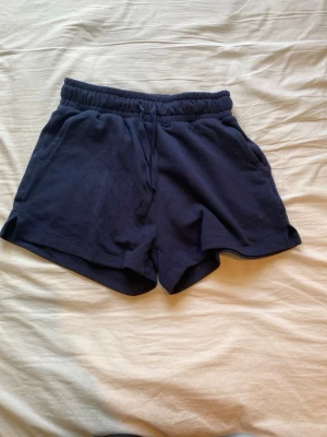 Mörkblå shorts med snörning Firefly - Mörkblå mjuka shorts från Firefly i storlek XS. Shortsen har elastisk midja med snörning och två sidofickor. Perfekta för varma dagar eller som chillplagg. Tillverkade i bomull för en bekväm känsla.