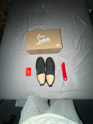 Svarta sneakers från Christian Louboutin - Snygga helsvarta sneakers från Christian Louboutin med klassisk låg profil och diskret design. Skorna har svart ovandel i mocka, svarta skosnören och den ikoniska röda sulan. Perfekta för dig som gillar stilrena och exklusiva sneakers.