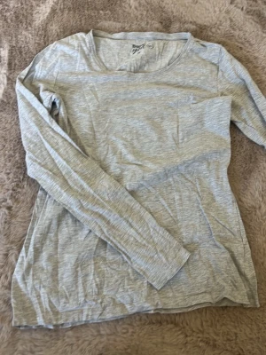 Ljusgrå långärmad topp Basic You - Ljusgrå långärmad topp från Basic You i mjuk ekologisk bomull. Enkel och stilren design med rund halsringning, perfekt att matcha med olika outfits. Materialet är tunt och skönt mot huden.