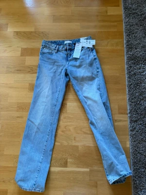 Blå straight jeans från Gina Tricot  - Säljer ett par ljusblåa straight jeans från Gina tricot , modell 'Scandi low straight jeans'. Klassisk femficksdesign, låg midja och raka ben. Materialet är 100% bomull och jeansen har en snygg vintage-wash. Perfekt för dig som gillar en avslappnad och trendig look.