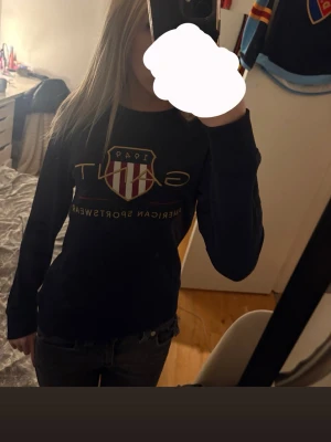 Marinblå långärmad topp från Gant - Marinblå långärmad topp från Gant med stort tryck och logga på bröstet i vitt, rött och guld. Knappt använt. Köptes för 1200❤️