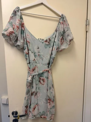 Klänning  - Blommig från Nelly med ett band i midjan 