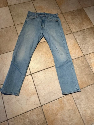 Levi's 501 W30 L30 - Ljusblå jeans från Levi's med klassisk rak passform och femficksdesign. Jeansen har en snygg vintage-look och är tillverkade i bomull. Perfekta för dig som gillar en avslappnad och tidlös stil.