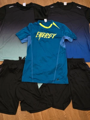 Träningskläder Herr M Svart och Blå/Grön *nyskick* - Hej! Säljer två kompletta träningsset från BURUITE – t-shirt och shorts i lätt, snabbtorkande polyester. Perfekt för gym, löpning eller vardagsaktivitet.   Dessutom ingår en extra t-shirt från Decathlon i polyester med snygg design och bekväm passform.  Färger: Svart, blå, grön. Storlek: M. Allt säljs i paket och är i fint skick – redo att användas direkt.  Mvh, Lucas