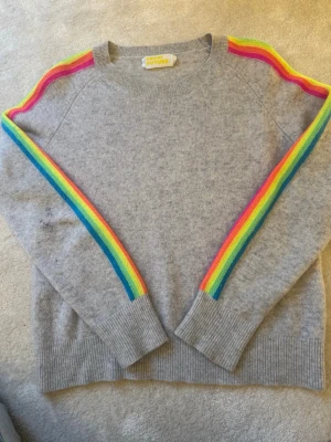 Grå stickad tröja med regnbågsränder - Grå stickad tröja från From Future med färgglada regnbågsränder längs ärmarna. Nypris ca 2000kr💕Har små defekter