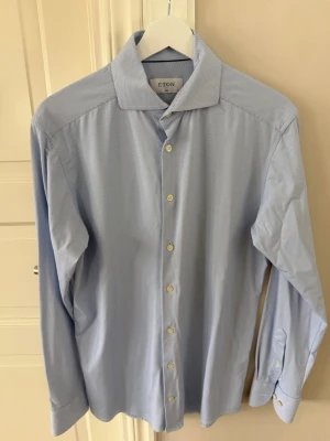 Blå mönstrad skjorta från Eton - Snygg blå skjorta från Eton med diskret mönster och klassisk krage. Skjortan har vita knappar och är långärmad, perfekt för en stilren look. Tillverkad i bomull för en skön känsla hela dagen.