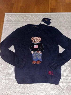 Polo Ralph Lauren Bear tröja marinblå – Ny med tag – Herr S/XS - Säljer denna marinblåa Ralph Lauren tröja med Björn som design. Den är storlek S men kan passa storlek XS. Skulle säga att den är liten i storlek.