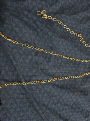 Svart quiltad axelväska med guldkedja - Snygg svart axelväska i quiltat mönster med guldfärgad kedjerem och matchande guldfärgat lås framtill. Väskan har en klassisk, rektangulär form och stängs med ett vridlås. Kan bytas till silverkedjerem också.