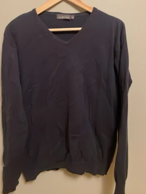 Mörkblå V-ringad tröja-Race Marine - Klassisk mörkblå V-ringad tröja från Race Marine. Tröjan har långa ärmar och ribbade muddar vid ärmslut och nederkant. Perfekt att bära över en skjorta eller t-shirt för en stilren look.