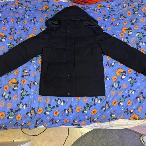 Svart dunjacka från Canada Goose - Säljer en svart dunjacka från Canada Goose med huva och klassisk patch på ärmen. Jackan har raka linjer, dragkedja och tryckknappar framtill samt två stora fickor. Perfekt för kalla dagar och riktigt snygg till streetwear-stilen. Lite kort vi resningar brorsan kläder, för han använder inte dessa typer av kläder längre. 