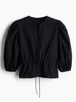 Svart blus - Säljer denna söta  blus med puffiga långärmar, knytband i halsen och midjan samt små dekorativa prickar i tyget. Blusen har knappar framtill och en lätt strukturerad look som ger en cool och modern känsla. Har endast använts 1 gång och därför säljes den!❣️