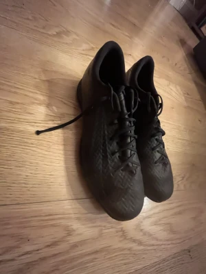 Svarta Nike sneakers med mönster - Säljer ett par svarta Nike sneakers med diskret mönster på ovandelen och klassisk snörning. Skorna har en låg profil och slitstark gummisula med tydligt greppmönster. Perfekta för dig som gillar stilrena och sportiga skor.