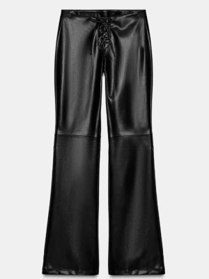 Svarta utsvängda byxor i skinnimitation - Slut sålda skinnbyxor ifrån Zara. Endast använda en gång.  Snygga svarta byxor i skinnimitation med utsvängda ben och snörning framtill i midjan. Byxorna har en låg midja och markerade sömmar vid knäna för en cool look. 