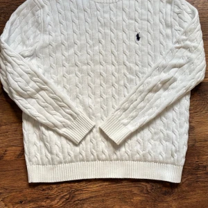 Vit kabelstickad sweatshirt från Polo Ralph Lauren - Storlek L men passar M, den är knappt använd. Stilren och grisch tröja. Priset är ej hugget i sten så kom gärna med förslag. Rökfritt samt djurfritt hus. 