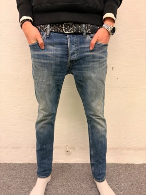 Blå skinny jeans från Jack & Jones - Modellen är 188cm 65kg|Pris går att diskuteras|Snygga blå jeans från Jack & Jones i skinny fit med klassisk femficksdesign och knappgylf. Jeansen har en tvättad look med ljusare partier och slitningar som ger en cool vibe. Perfekta för dig som gillar en smal siluett och vill ha ett stilrent plagg i garderoben.