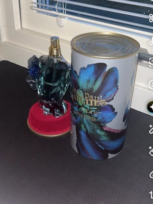 Jean Paul Gaultier Le Beau Flower Edition - Unik parfym från Jean Paul Gaultier, Le Beau Flower Edition. Flaskan har en blågrön glasdesign formad som en manlig torso med en dekorativ blå blomma på axeln. Kommer med en snygg cylinderformad förpackning med blommotiv.